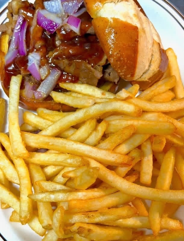 BBQ sandwich piled with red onion and crispy fries