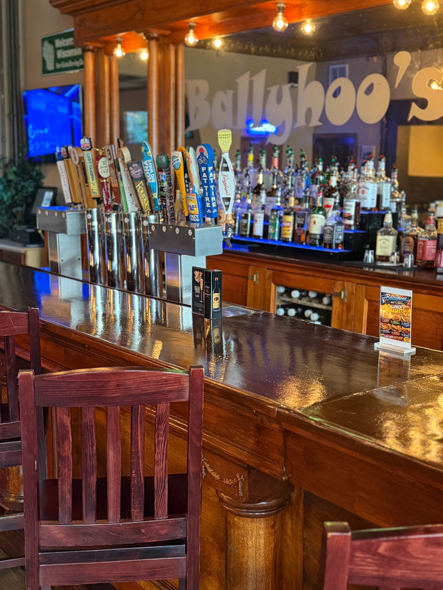 Polished wooden bar top with craft tap handles and Ballyhoo's mirror
