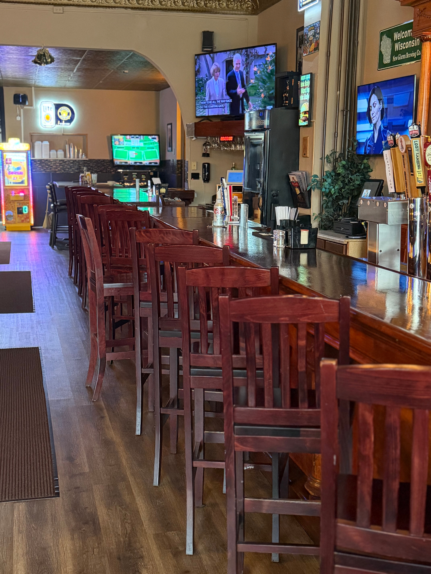 Long wooden bar with stools and multiple TVs inside Ballyhoos